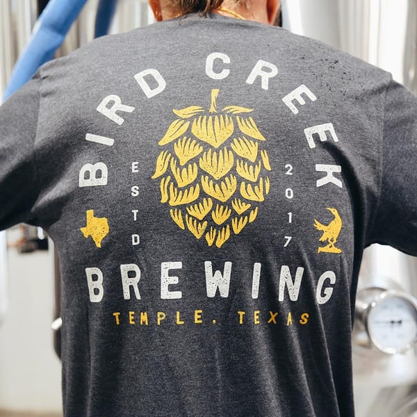 Back of a person wearing a gray Bird Creek Brewing long-sleeve shirt with a hop design.